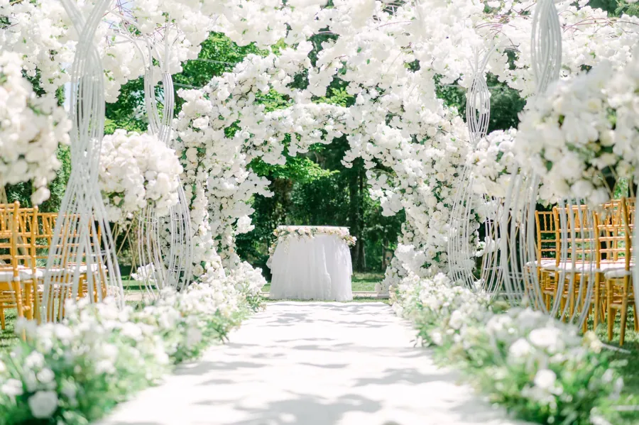 A long aisle running under a tunnel of white florals and greenery
